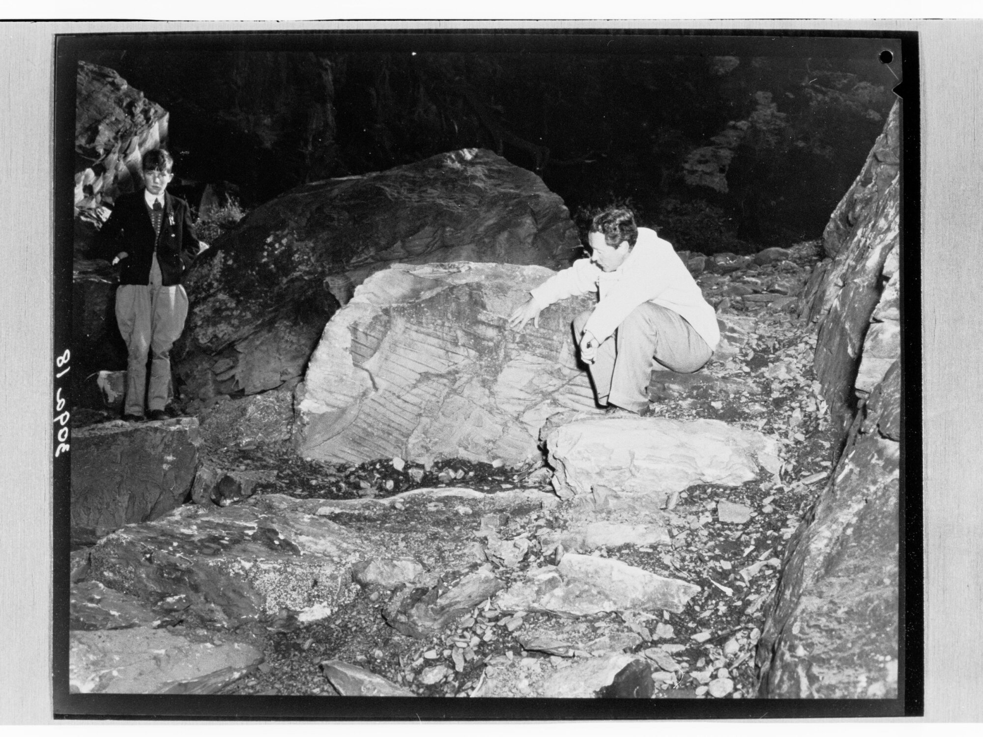 Man sitting on ground looking at markings on large rock