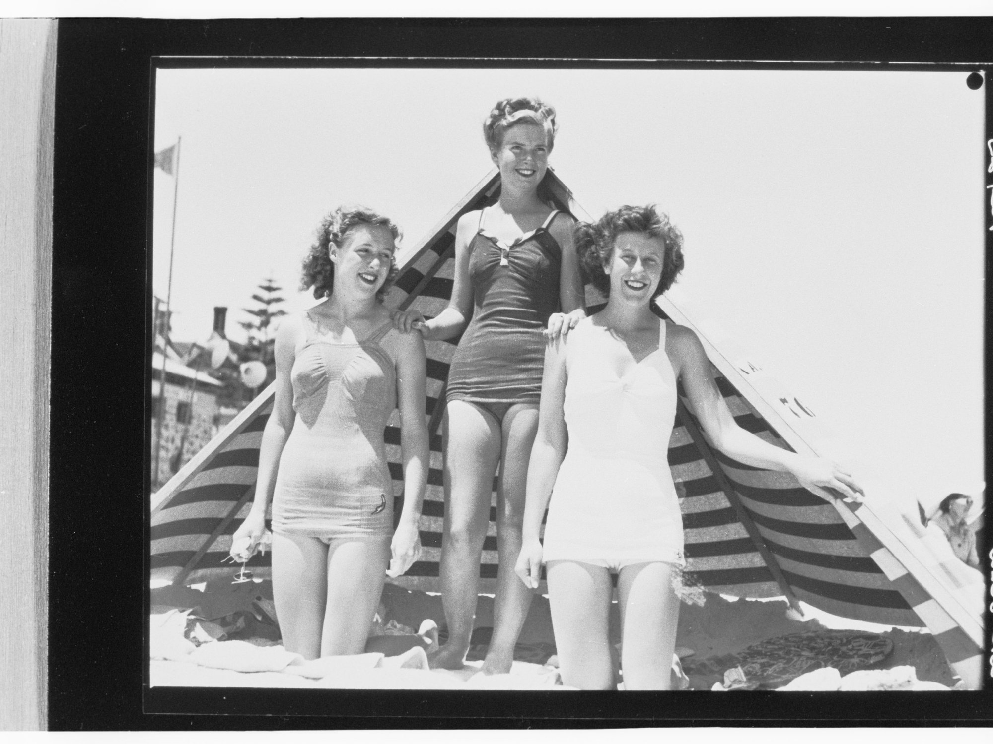 Three women on beach in front of sunshade