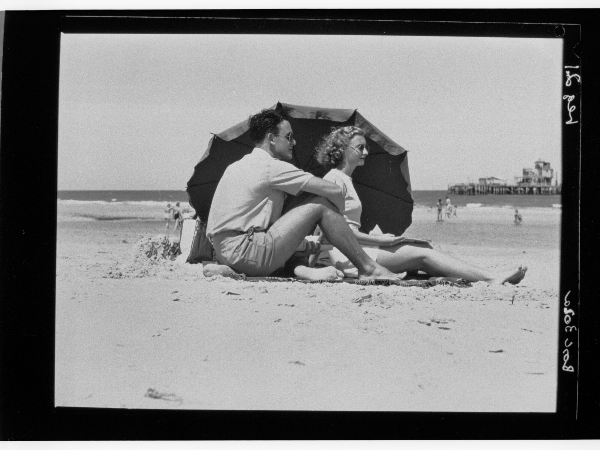 Man and woman sitting on beach under umbrella