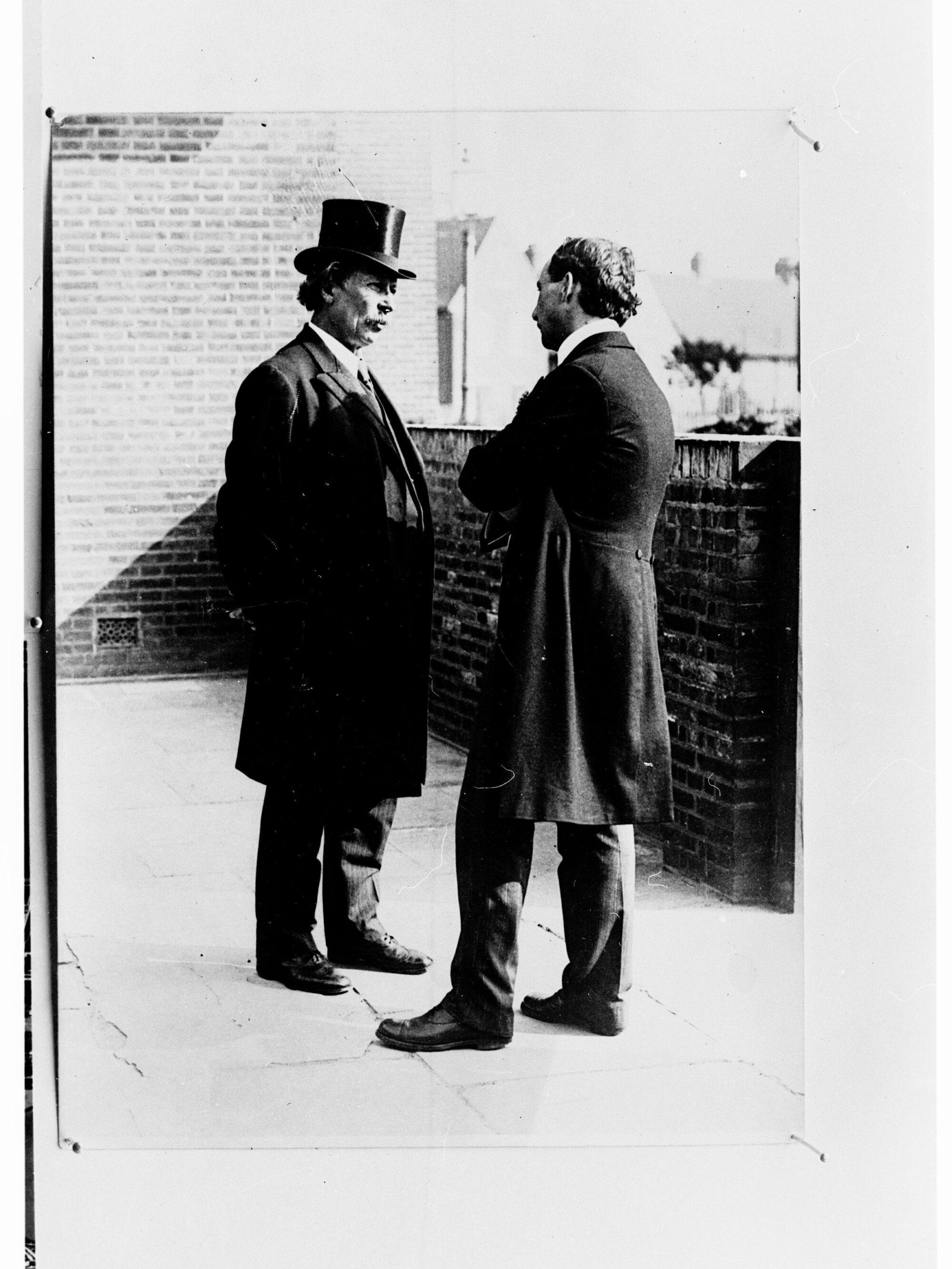 Photograph of two gentlemen standing talking to each other - man in the top hat is Lloyd George