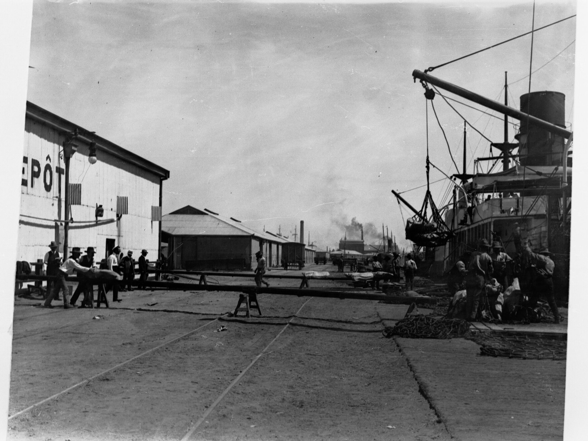 Boats berthed showing wharfies unloading goods from ship