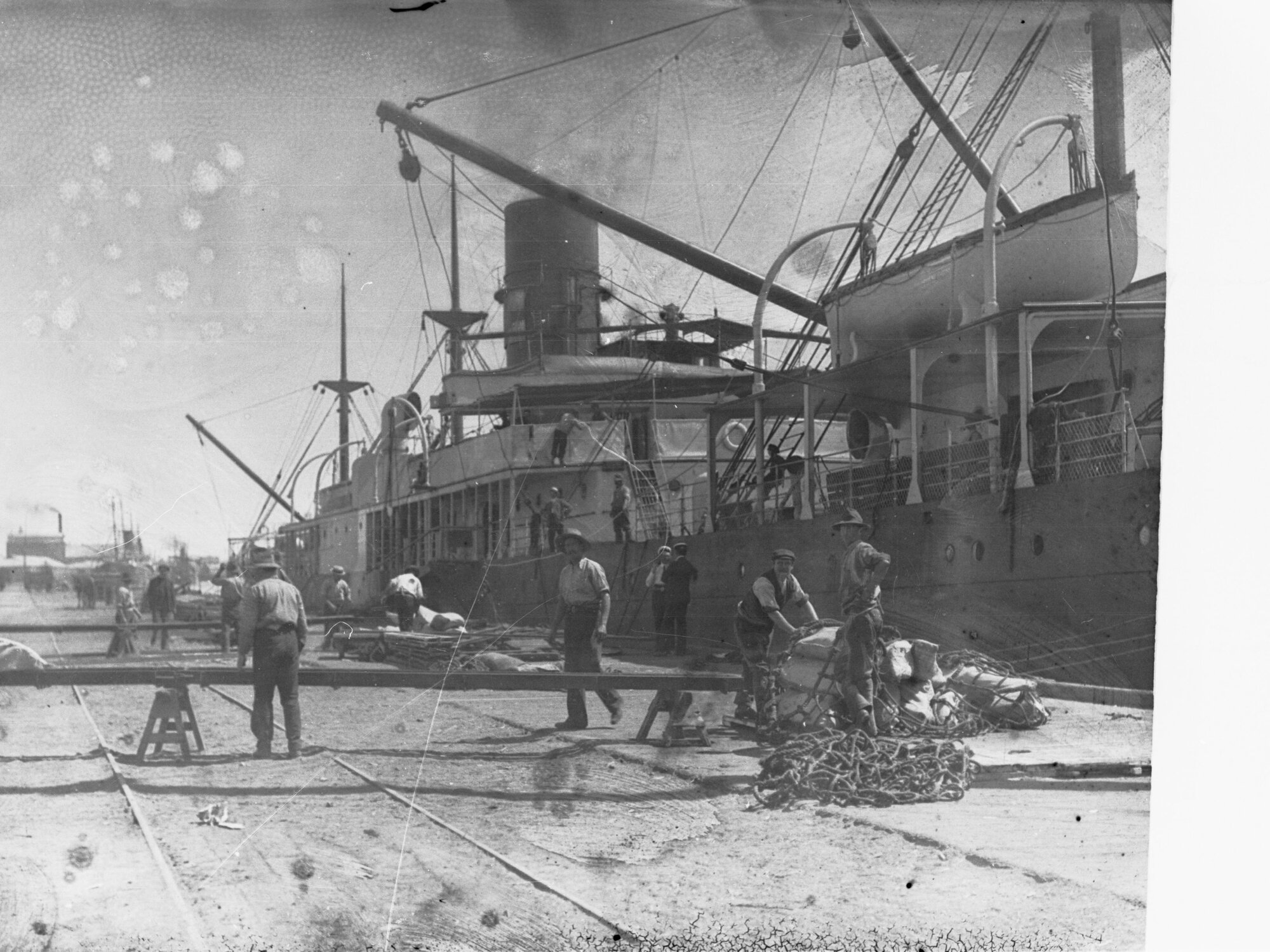 Ship berthed showing men working to unload goods off ship.