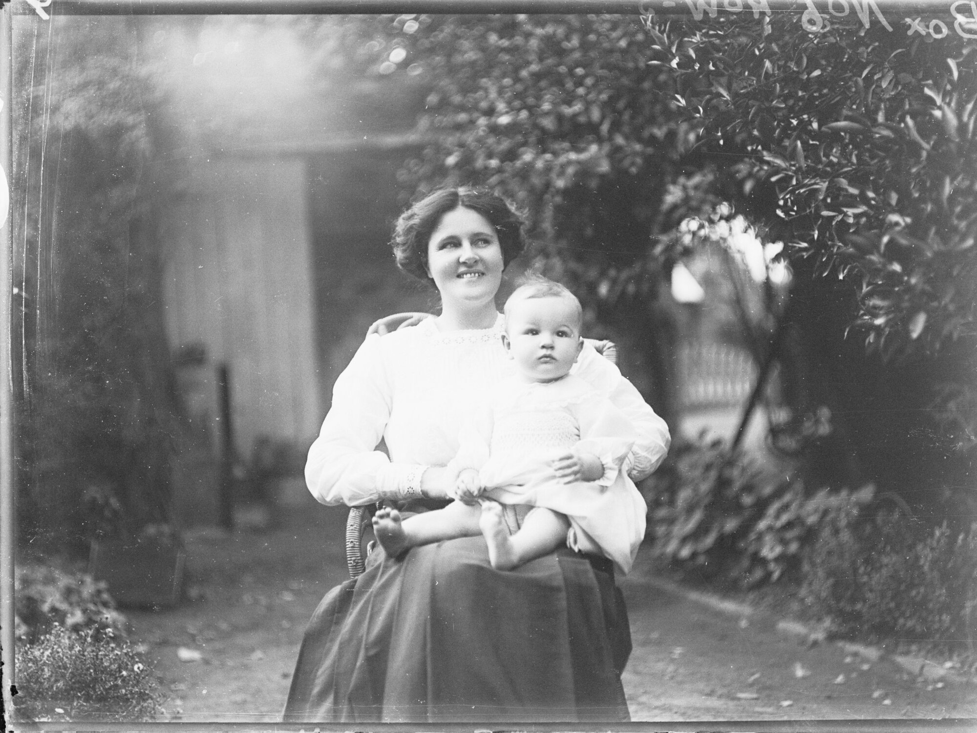 Mother with baby on knee sitting in garden 