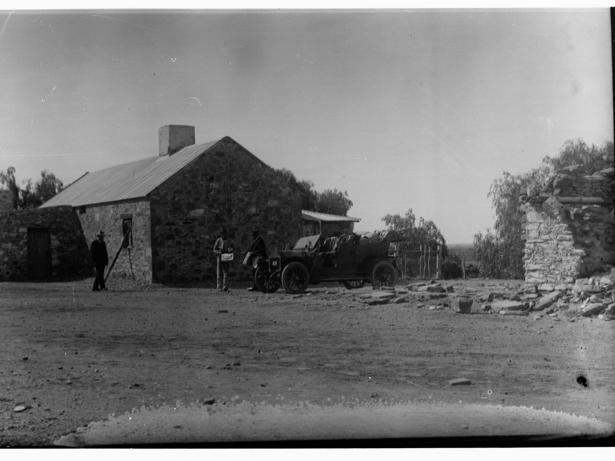 Stone house showing automobile and men in front