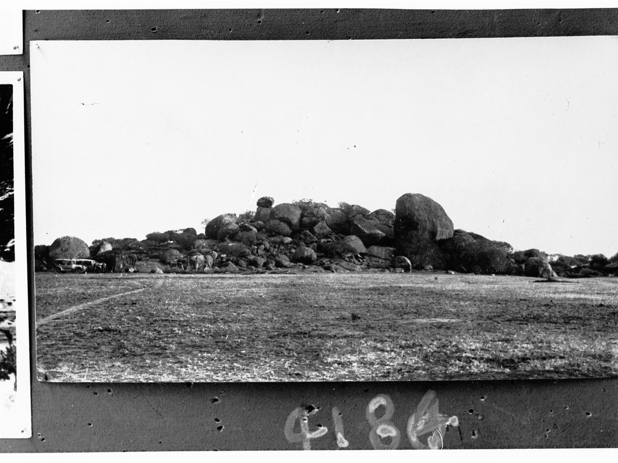 Rocky outcrop, Central Australia - motor vehicles in front of rocks - location unknown