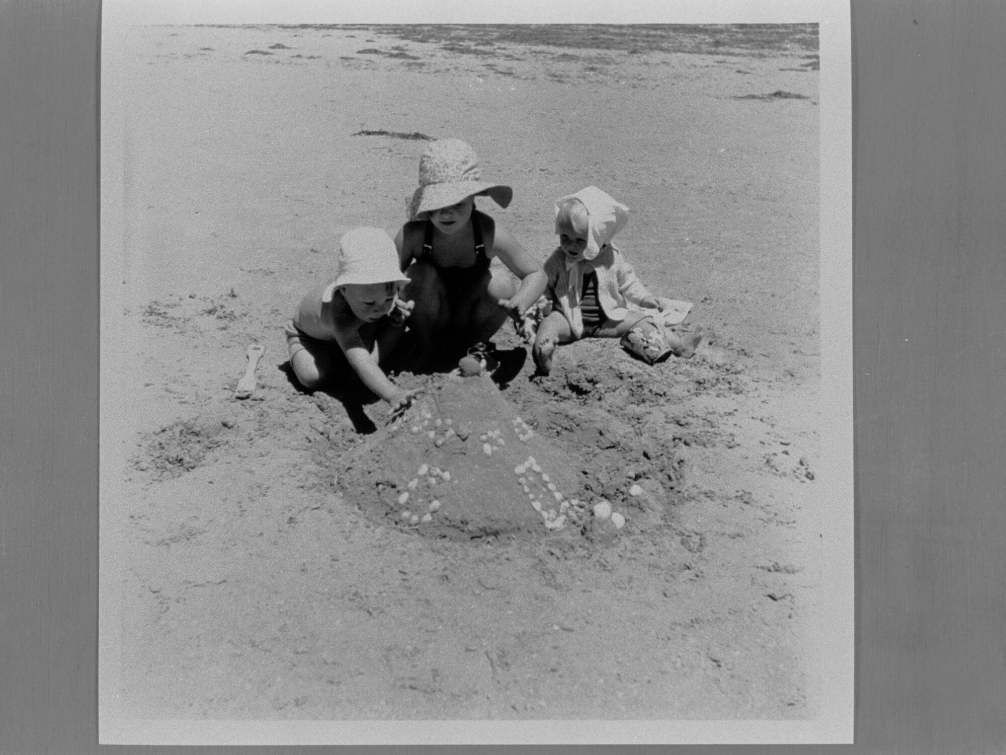Three young children playing in the sand