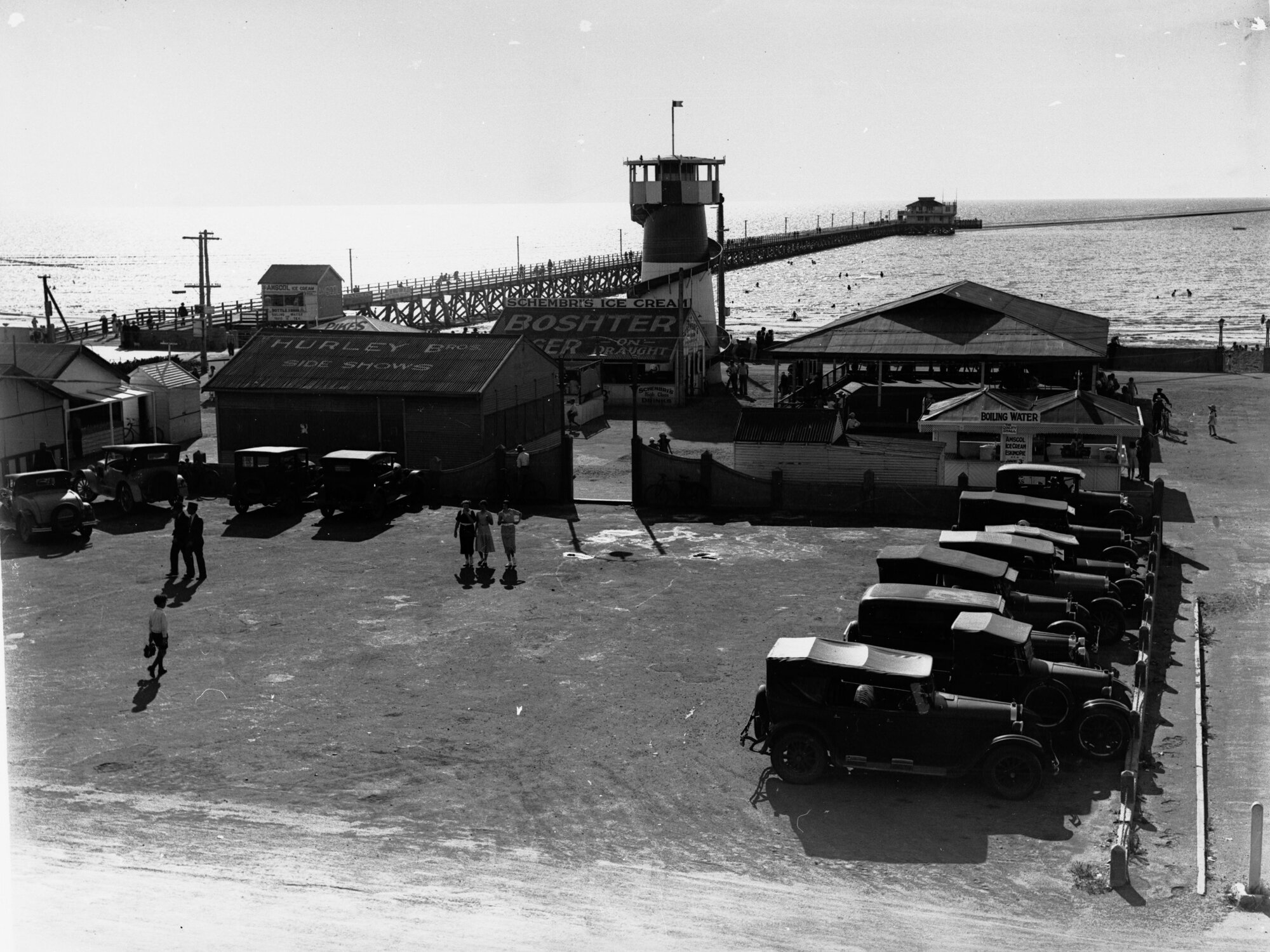 Semaphore showing the street before the beach and automobiles in parking area