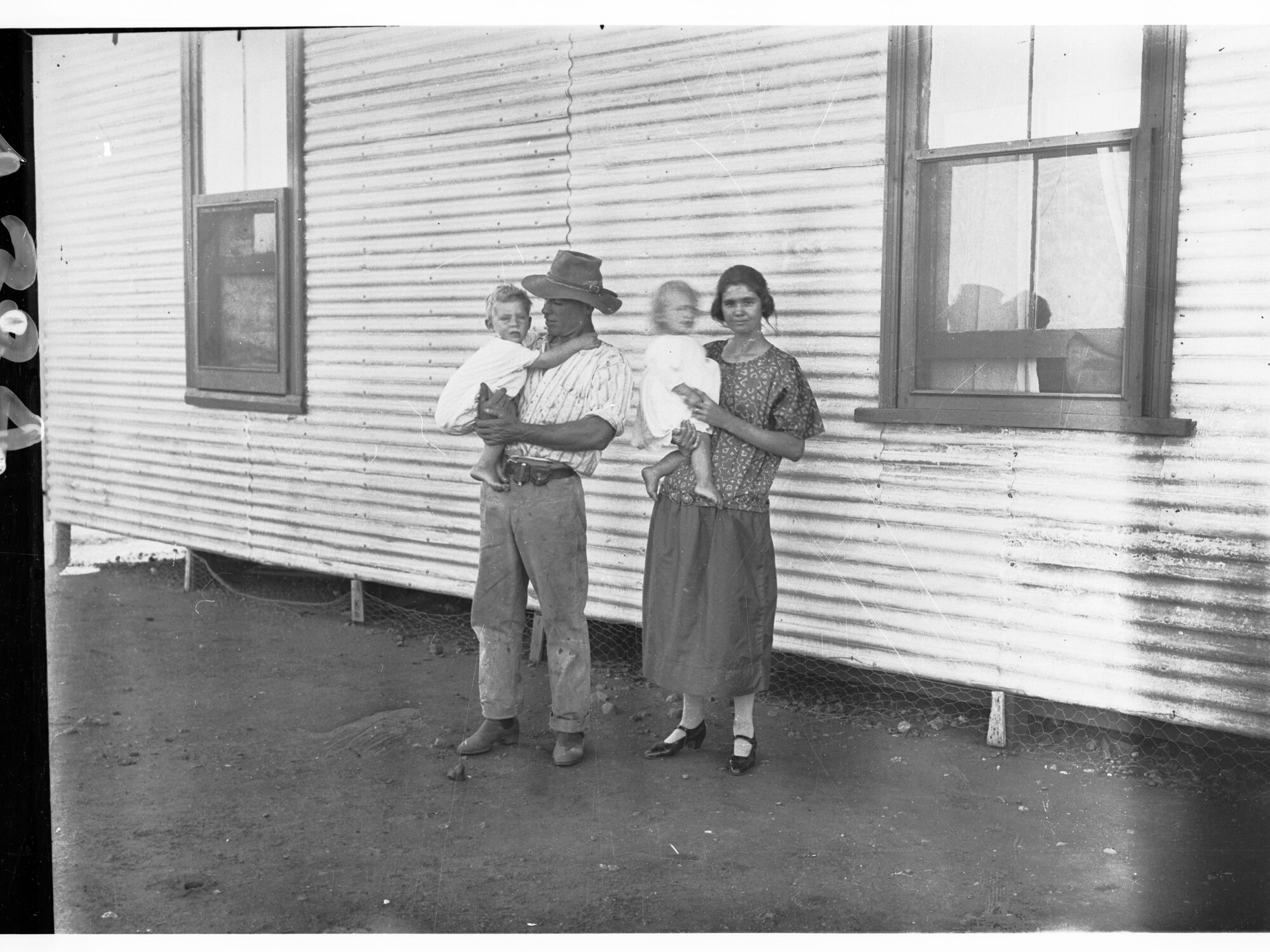 Man and woman standing in front of a building - both the man and woman are holding a young child