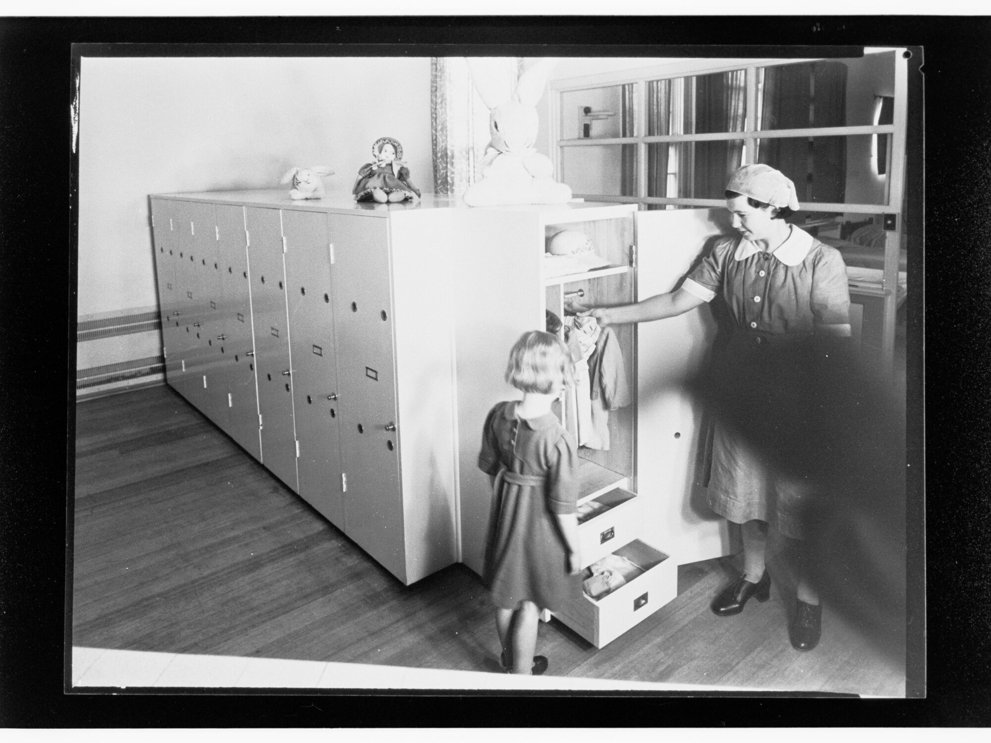 Children's Welfare Department - nurse's aide showing girl clothes in wardrobe