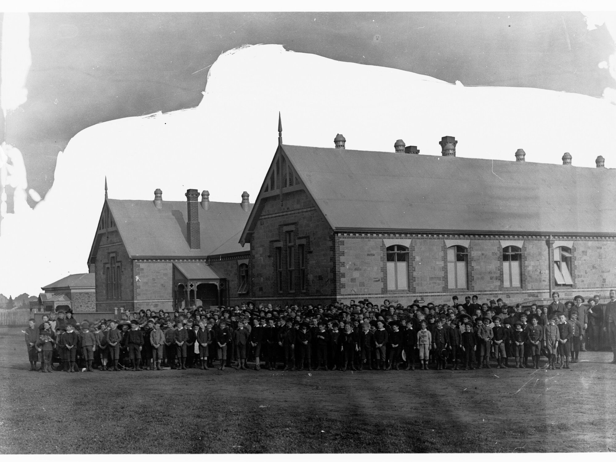 Picture of a school with large group of children in front of building