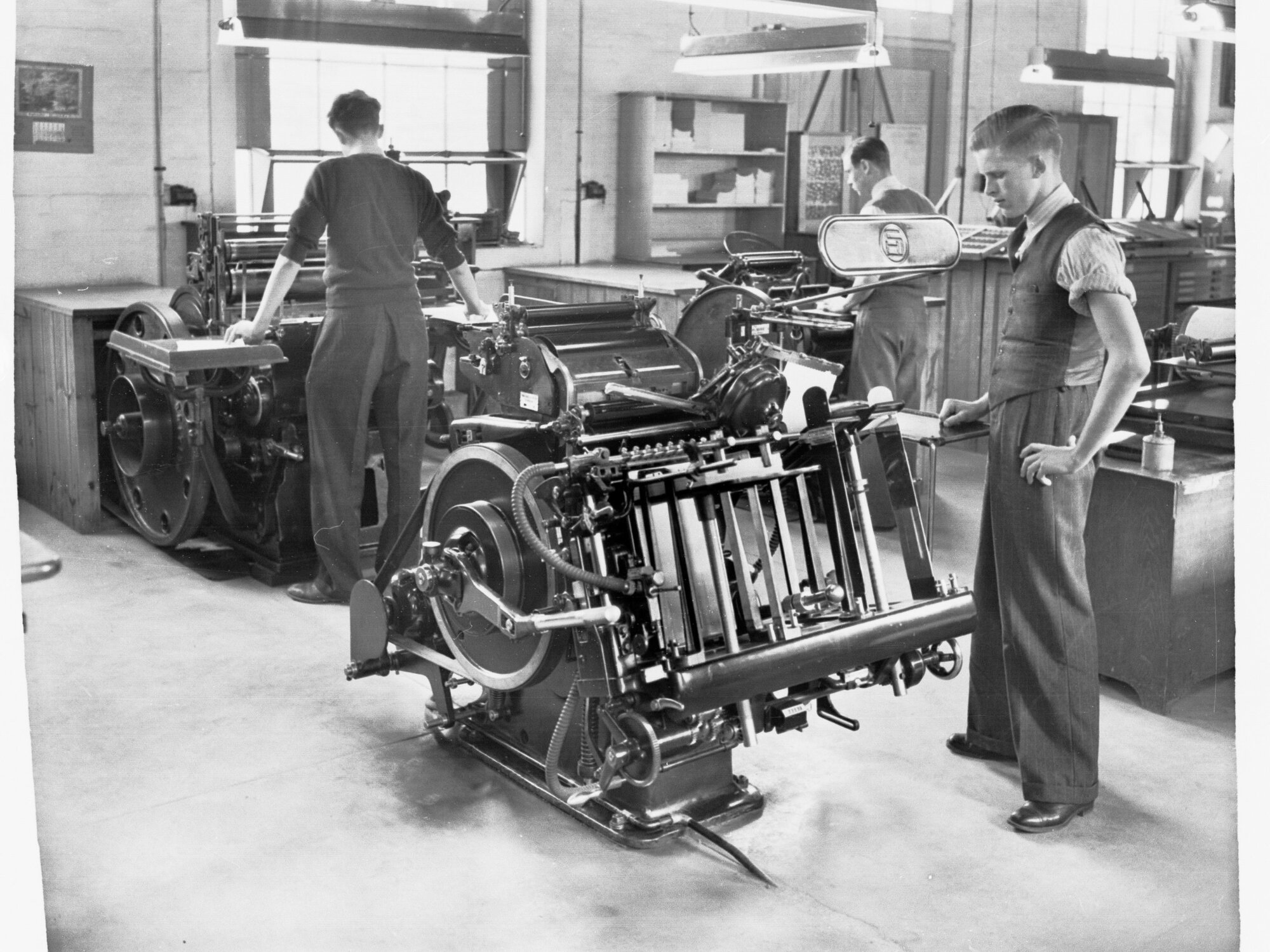 Printers Trade School Showing Two Young Men Working Printing Machine