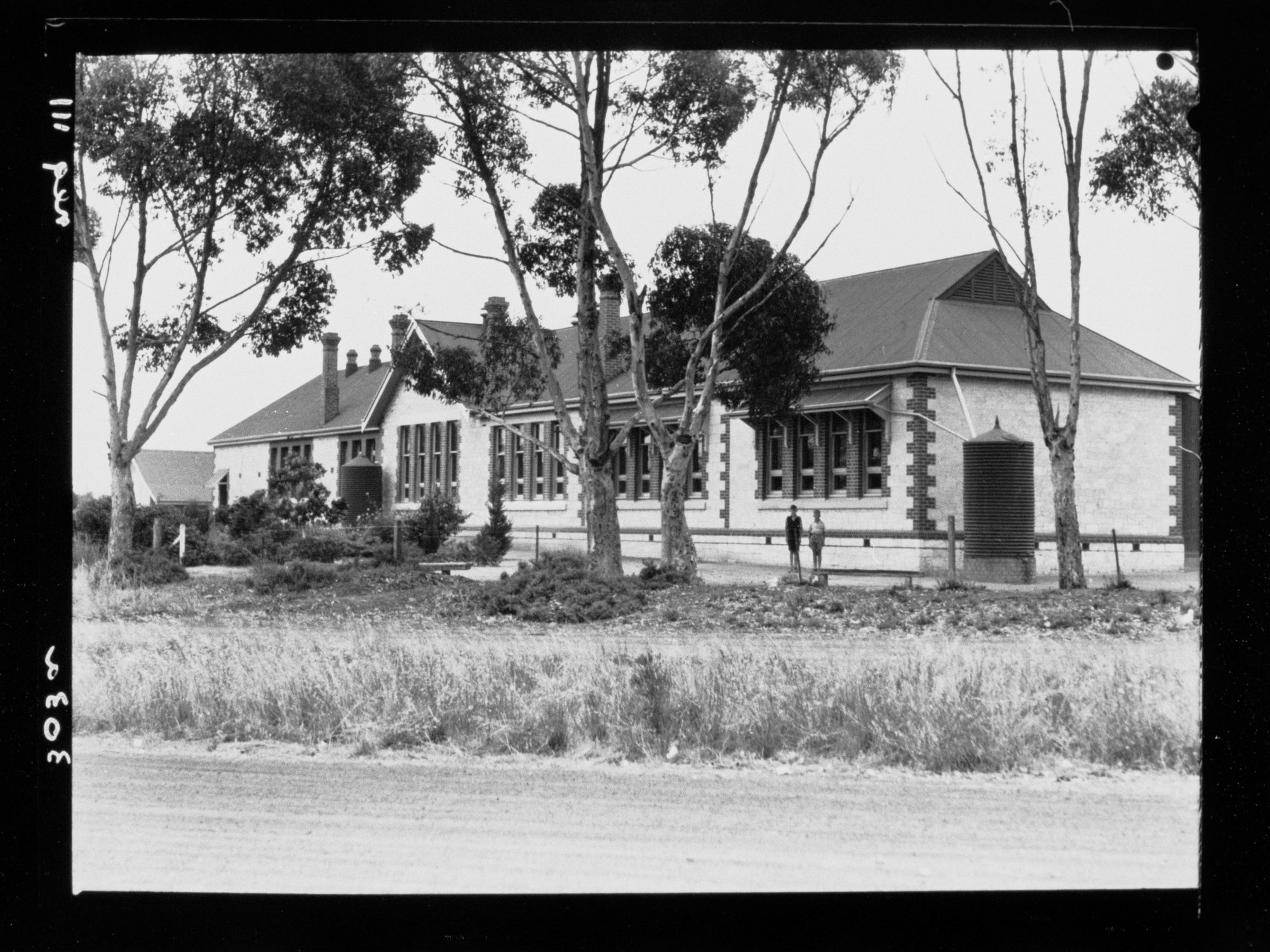 Two boys standing in front of building (school?)