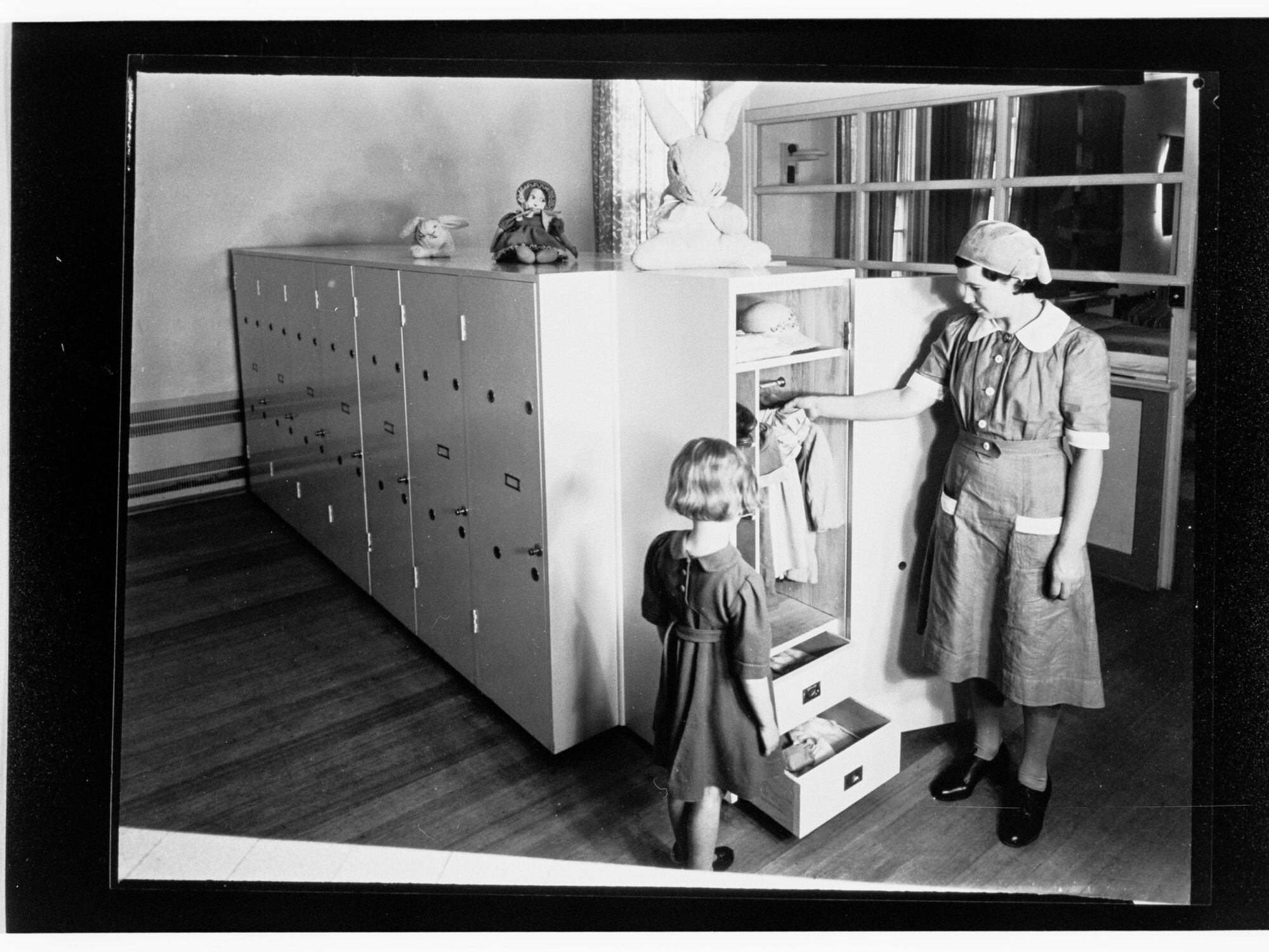 Children's Welfare Department - nurse's aide showing girl clothes in wardrobe