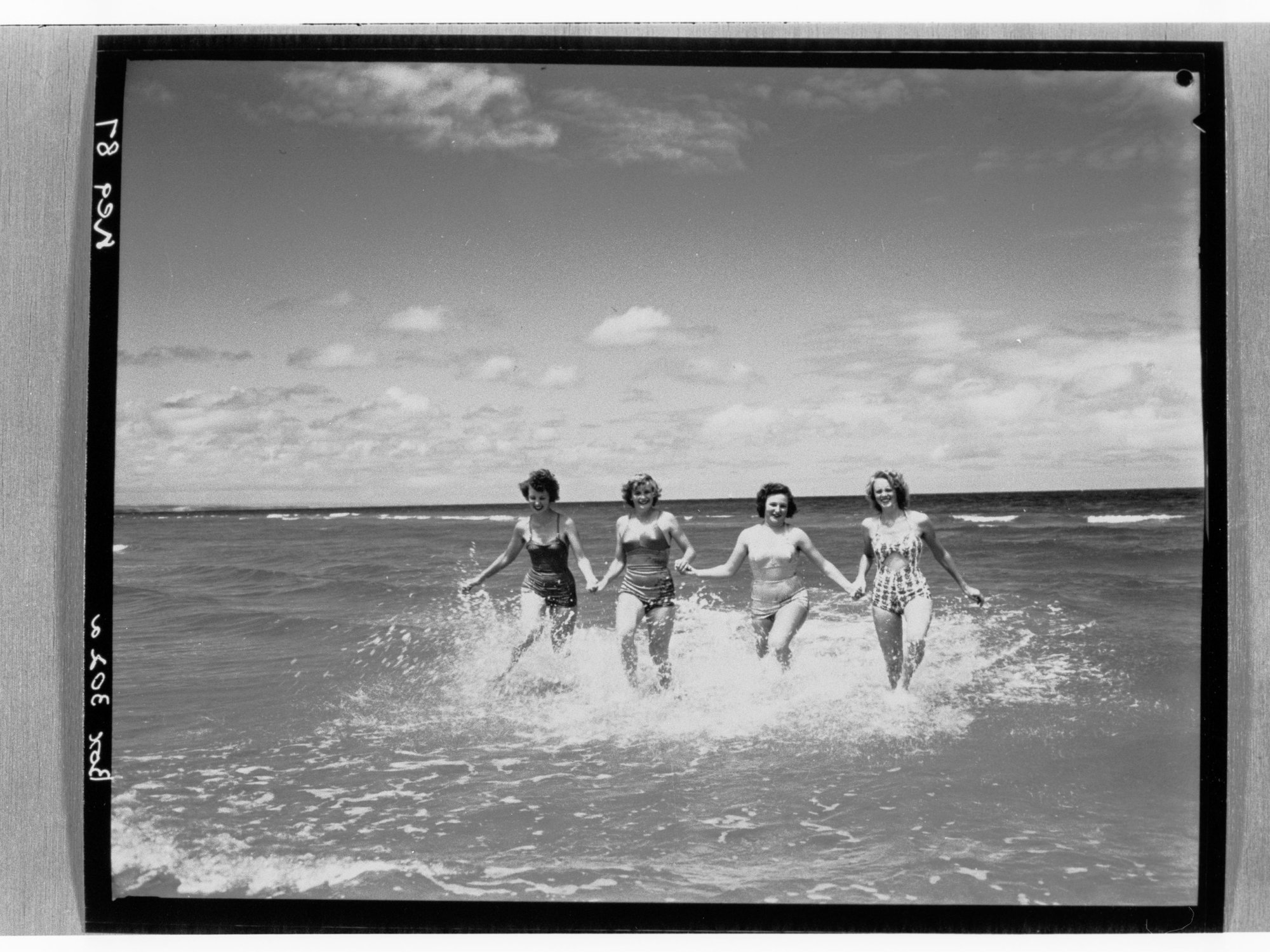 Four women holding hands in water