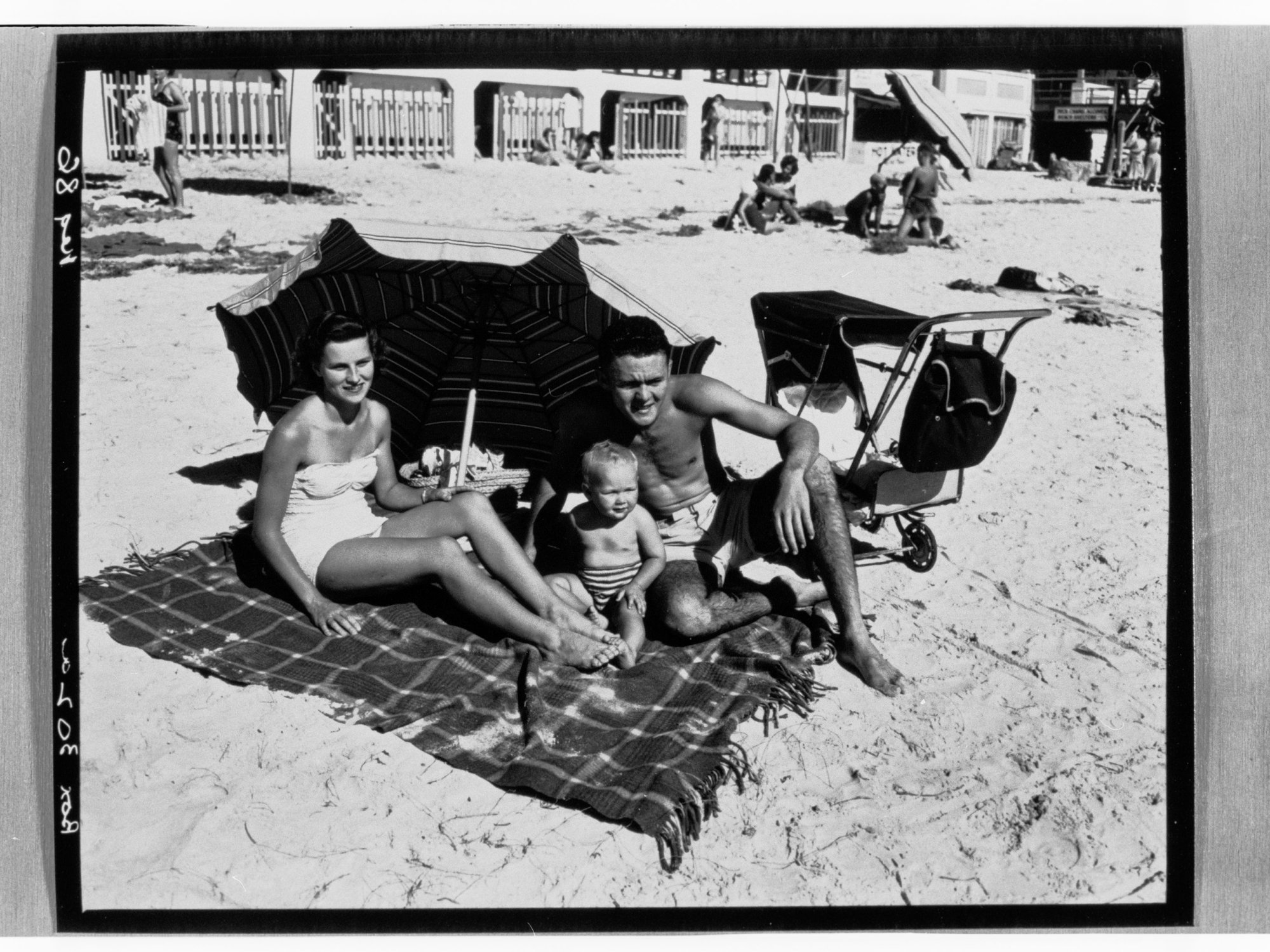 Henley Beach - Man, woman and baby sitting on beach under umbrella