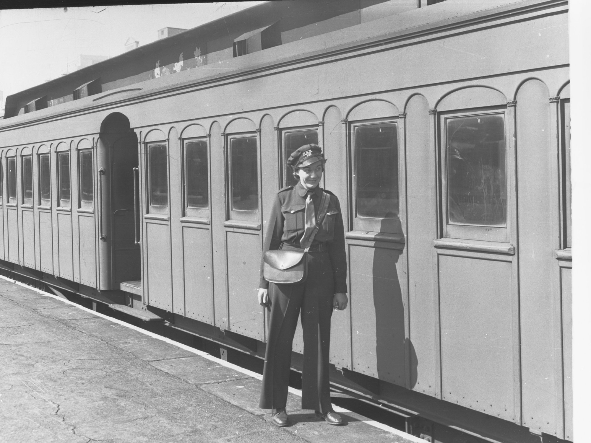 South Australian Railways female ticket collector showing carriage in the background