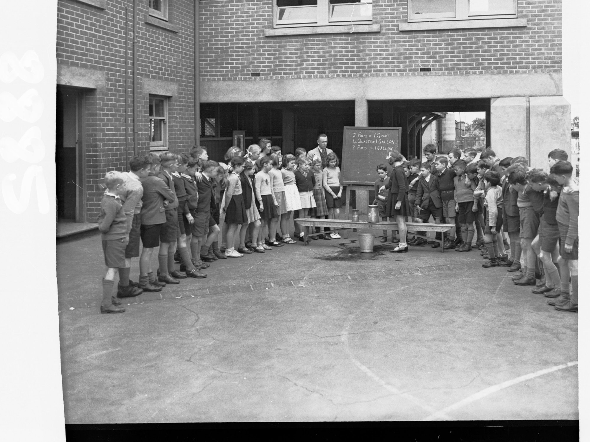 Goodwood Primary School Showing Children and Teacher - Showing Children Learning to Measure Pint Quart and Gallon Measures