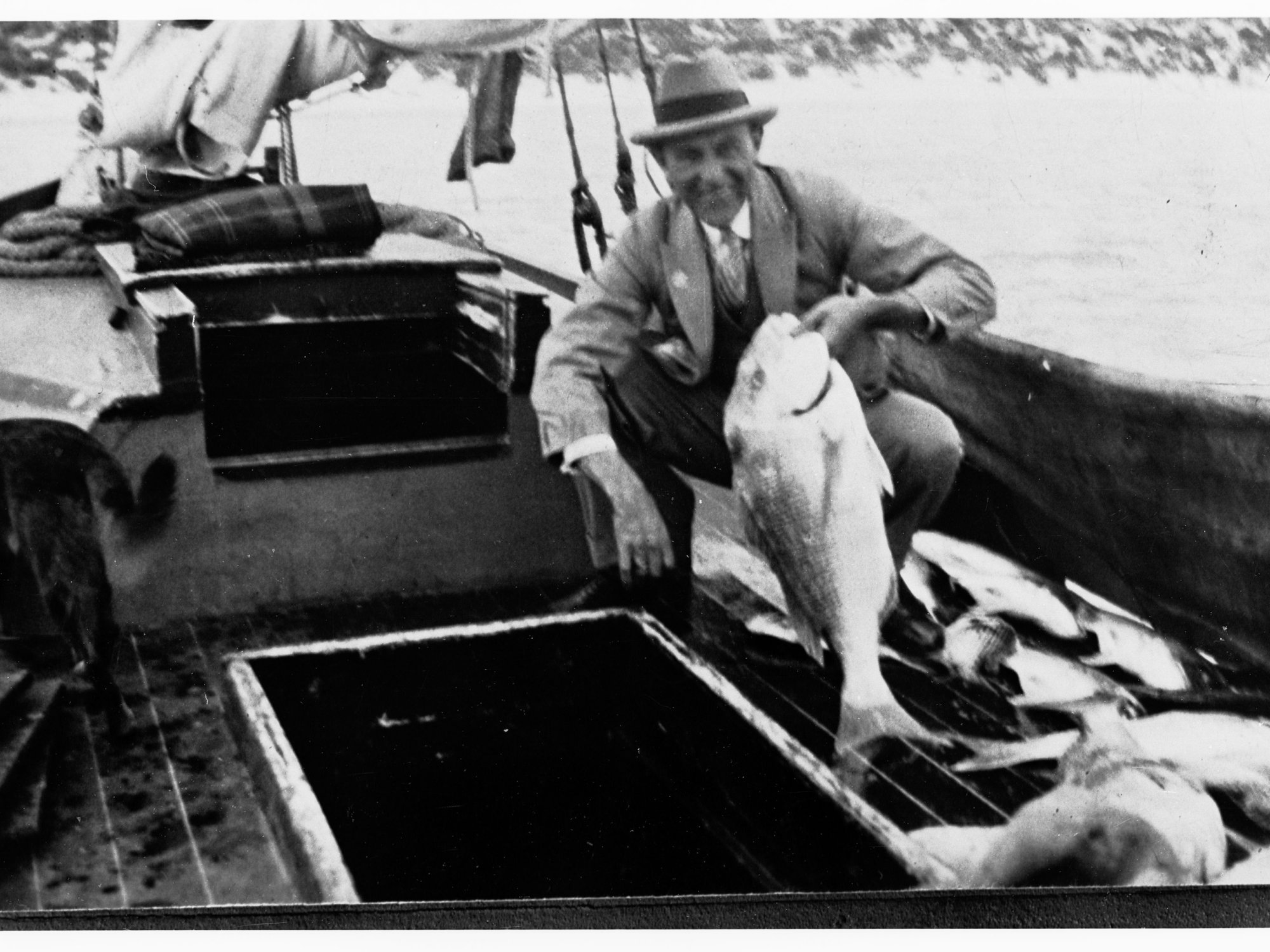 Man on a fishing boat holding up a fish