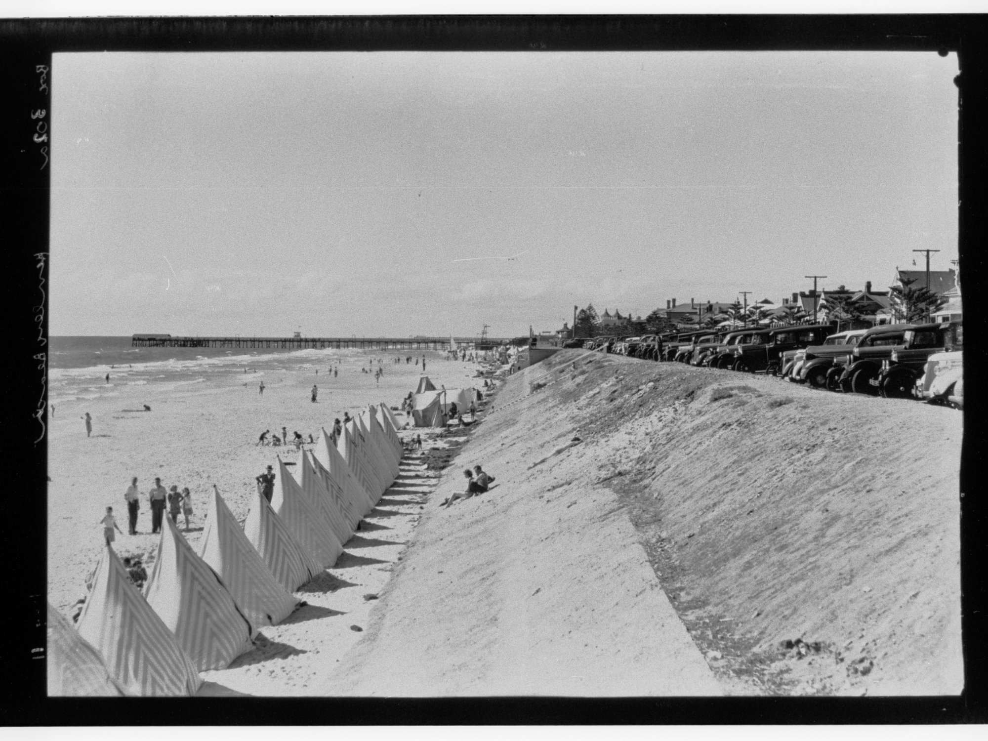 Row of beach tents and pier in background