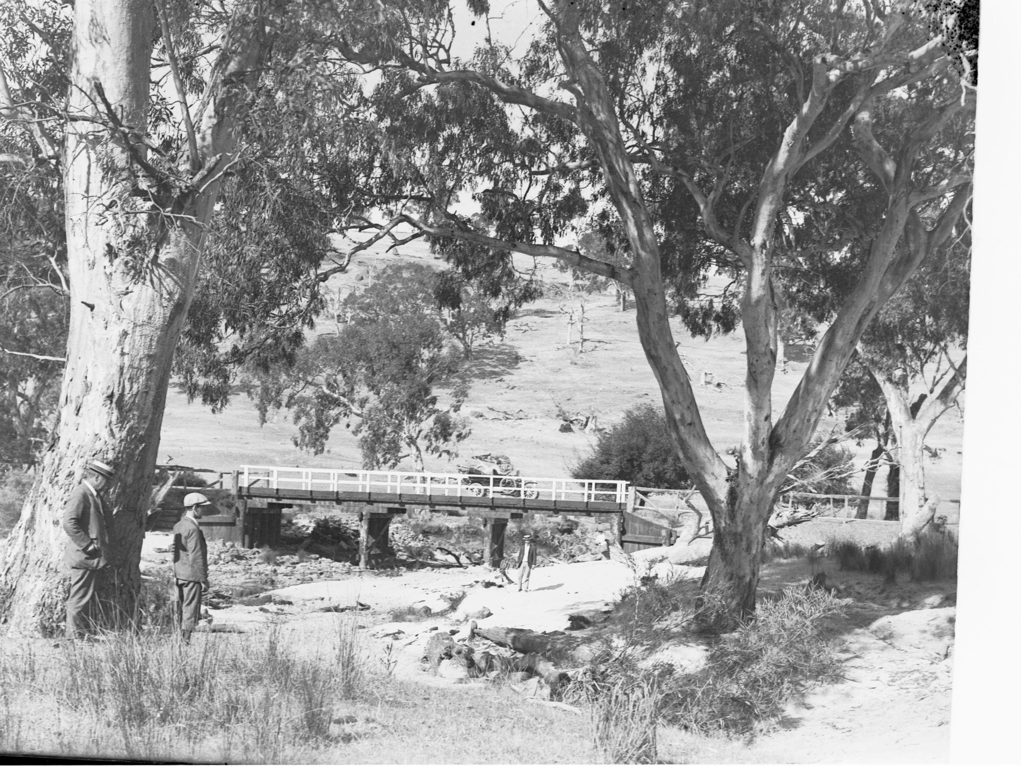 Rural View with Bridge Crossing River, Man in Foreground, Automobile on Bridge
