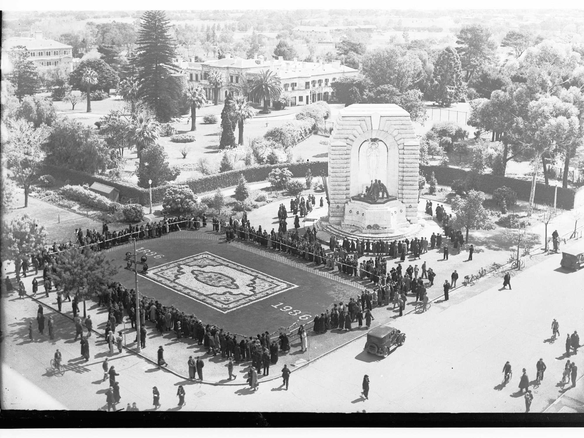 Crowd inspecting the floral carpet and flowers on the War Memorial at corner of Kintore Avenue and North Terrace - Flower Day 1936