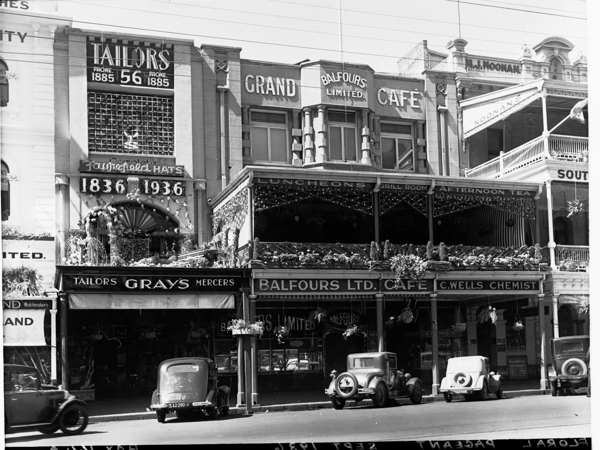 Buildings decorated on King William Street for State centenary, showing Balfours grand cafe, automobiles parked in street