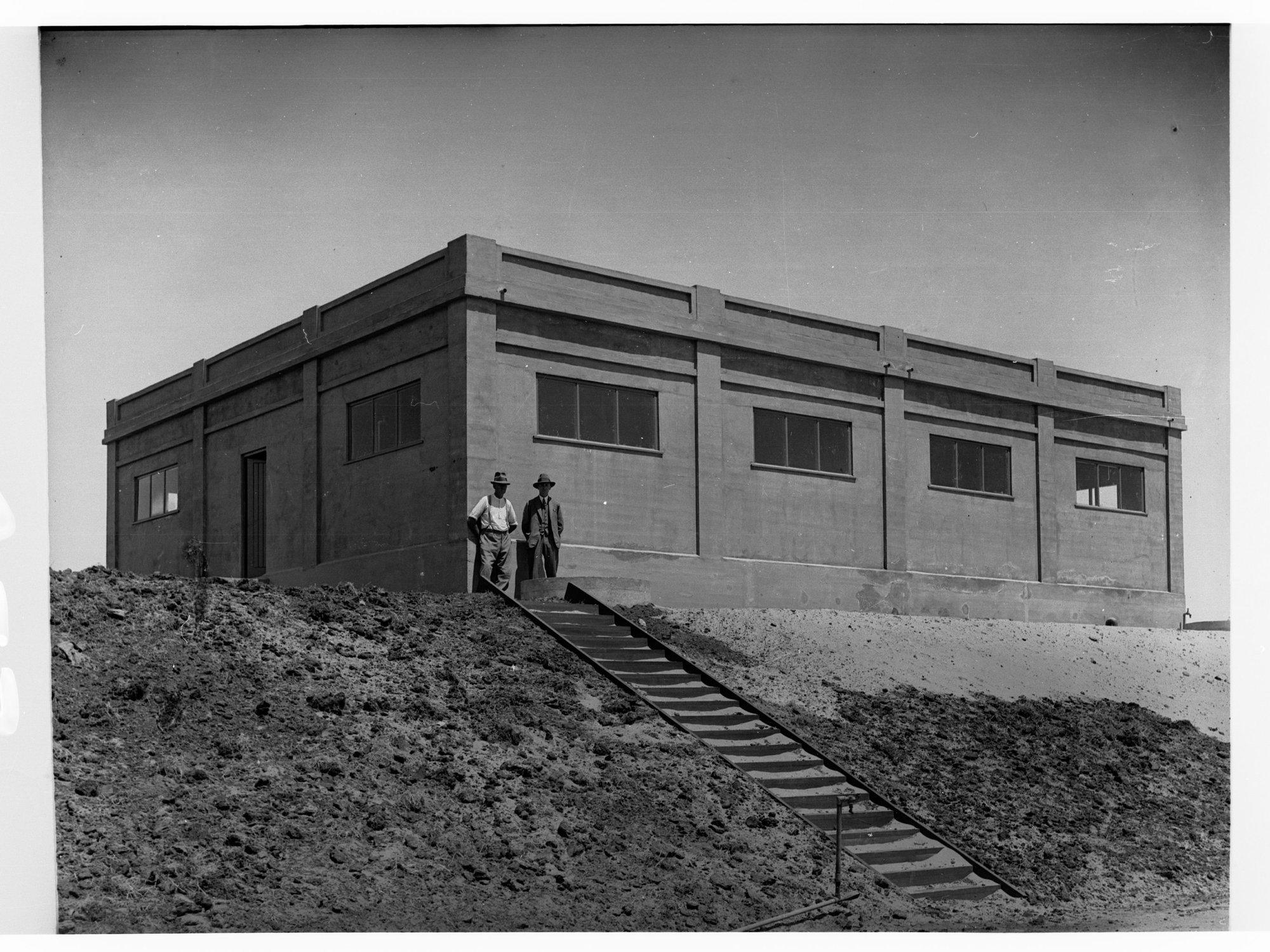 Glenelg Sewers showing men at top of a staircase near a building