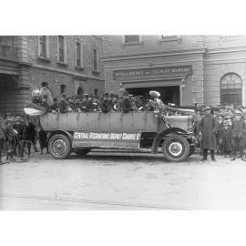 Decorated Charabanc outside Intelligence and Tourist Bureau, King William Street - band members holding their instruments are in car for the official opening of Central Recruiting Depot on Currie Street.  (Charabanc is displaying sign which says "Central 