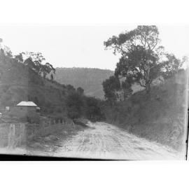 View in Mount Lofty Range showing automobile on dirt road and a cottage