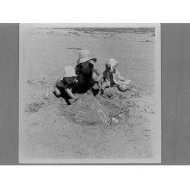Three young children playing in the sand