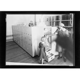 Children's Welfare Department - nurse's aide showing girl clothes in wardrobe