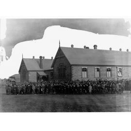 Picture of a school with large group of children in front of building