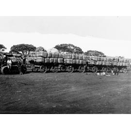 Bales of wool loaded on wagons being towed by a caterpillar tractor - wool is from Yardea Station (west of Port Augusta)
