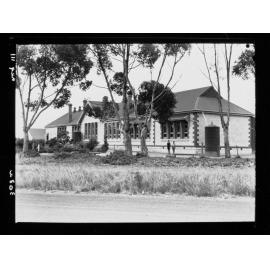 Two boys standing in front of building (school?)