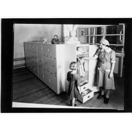 Children's Welfare Department - nurse's aide showing girl clothes in wardrobe