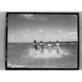 Four women holding hands in water
