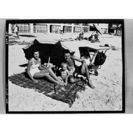 Henley Beach - Man, woman and baby sitting on beach under umbrella
