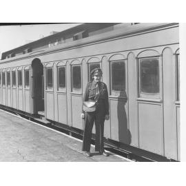 South Australian Railways female ticket collector showing carriage in the background
