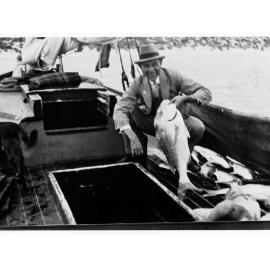 Man on a fishing boat holding up a fish