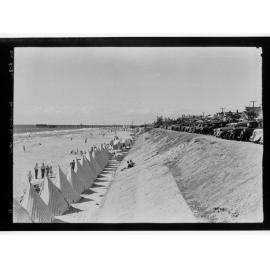 Row of beach tents and pier in background