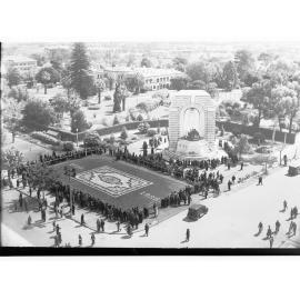 Crowd inspecting the floral carpet and flowers on the War Memorial at corner of Kintore Avenue and North Terrace - Flower Day 1936