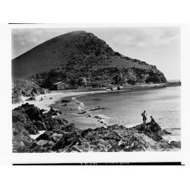 Coastal view showing boat sheds in the distance and people on rocks - Second Valley